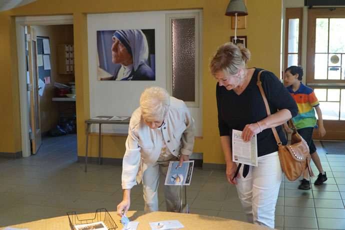 Yvonne Miller and Theresa Rennirt pick up St. Teresa of Kolkata prayer cards prior to Mass Sept. 4 at Blessed Teresa of Calcutta Church in Fairdale. Mother Teresa was canonized by Pope Francis on Sept. 4 during a Mass in St. Peter's Square.