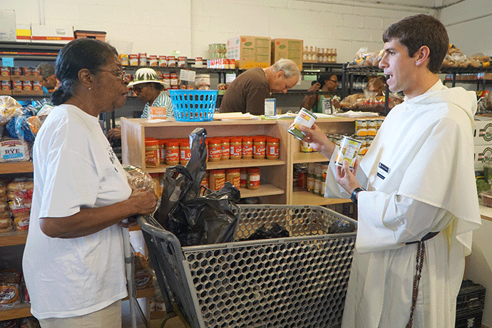 Brother Frassati Davis assists a client at the Society of St. Vincent de Paul’s Food Pantry. Brother Davis and Brother Bartholomew Calvano — both students at the Dominican House of Studies in Washington, D.C. — are spending their summer living at St. Louis Bertrand Church and working at St. Vincent de Paul. (Record Photo by Jessica Able)