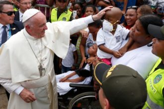 Pope Francis greets a sick child near the Talitha Qum homeless shelter in Cartagena, Colombia, Sept. 10. The pope cut his head in the popemobile when it braked suddenly. (CNS photo/Paul Haring)