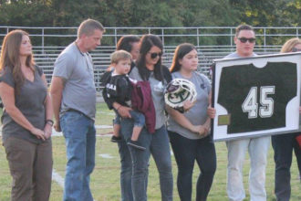 Andy Rodman, the brother of police officer Nicholas Rodman, held a framed number 45 jersey during a football game on Holy Cross High School's campus Sept. 8. A similar one will hang in the school's building. (Photo Special to The Record by Holy Cross High School)