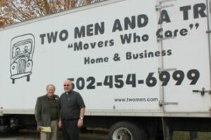 Deacon Lucio Caruso of Catholic Charities and Father Chris Lubecke stand in front of the moving truck that picked up the donated household goods collected by parishioners of St. Catherine Church in New Haven, Ky.
