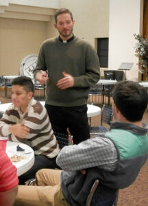 Father Michael Wimsatt, director of the Vocation Office, gave the young men directions for a group discussion during the St. Andrew Dinner. (Record Photo by Ruby Thomas)